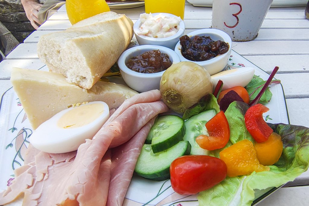Ploughman's Lunch -ateria, jossa on cheddarjuustoa, kinkkua, keitetty kananmuna, patonkia, salaattia, kurkkua, paprikaa, pikkelöity sipuli sekä pieniä kulhoja pikkelöidyille lisukkeille.