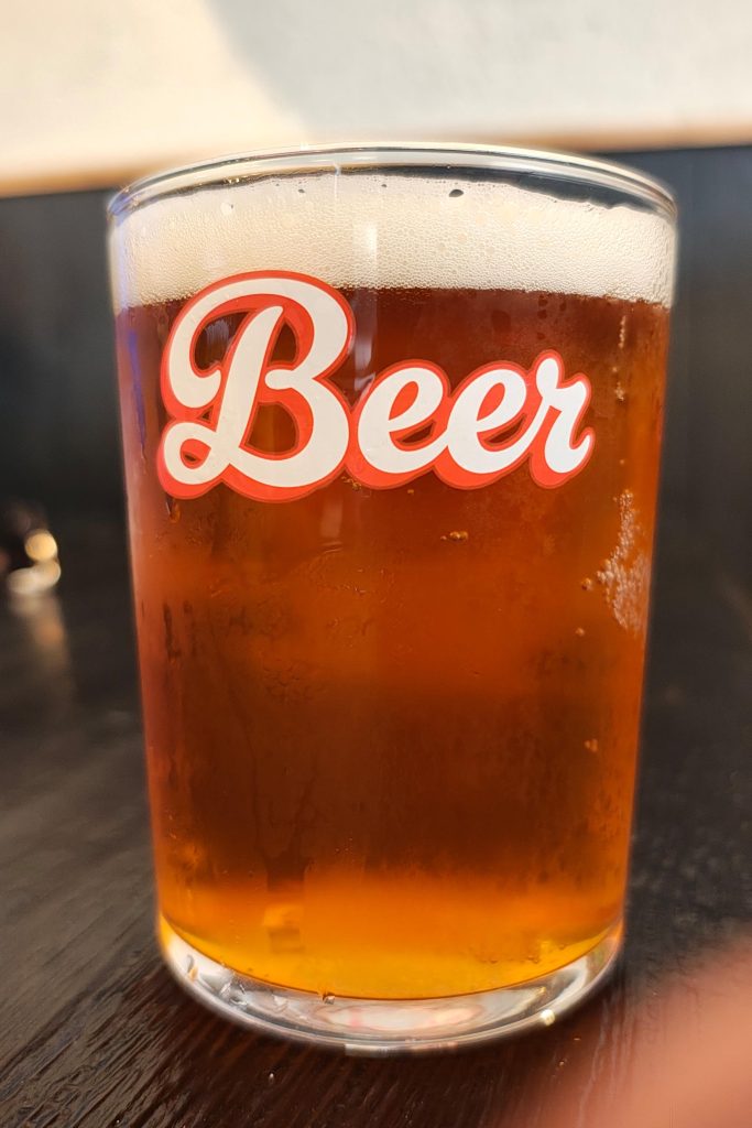 Lasillinen vaaleanruskeaa olutta, jonka lasissa lukee Beer.